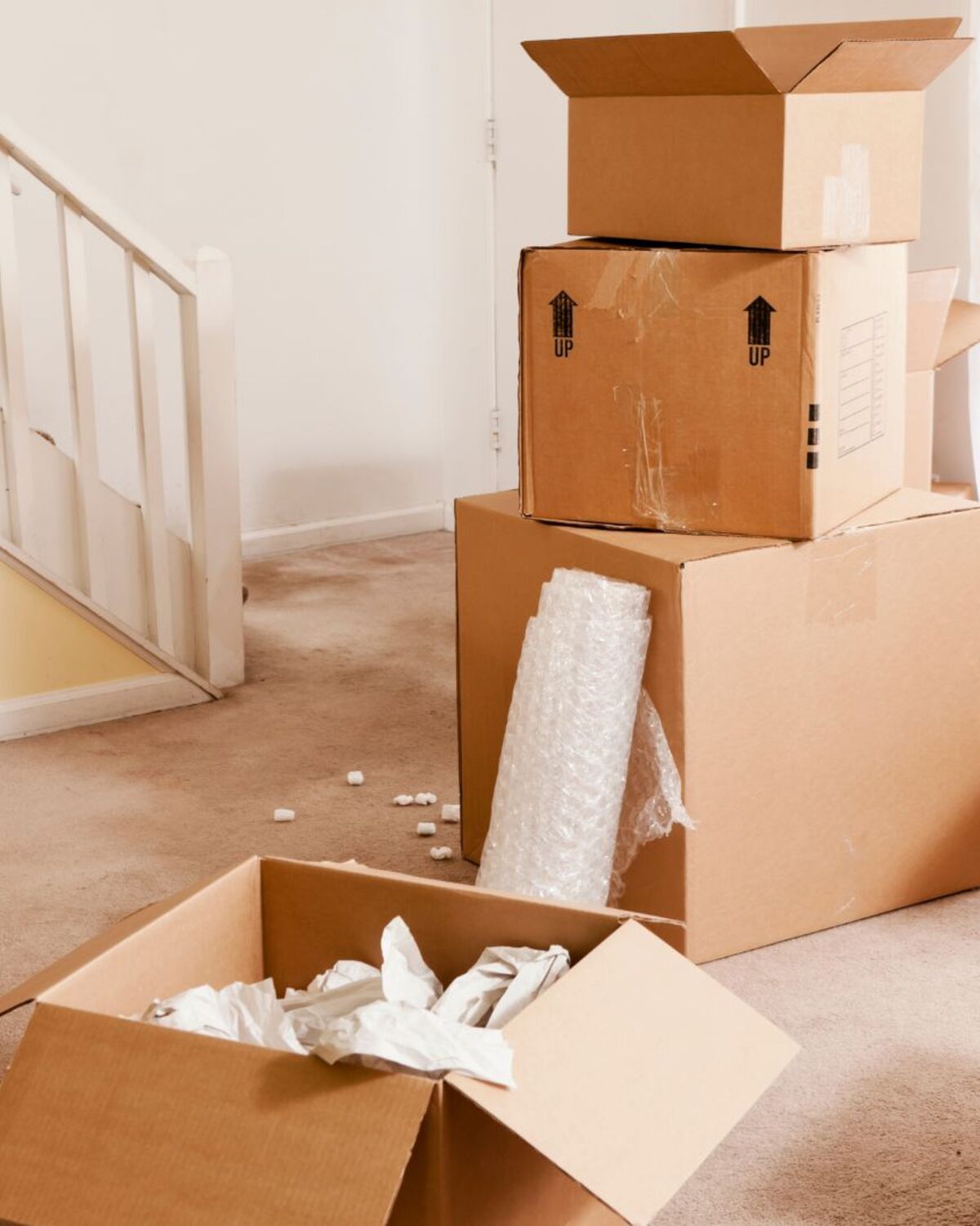 Packed boxes and bubble wrap staged near an apartment stairwell