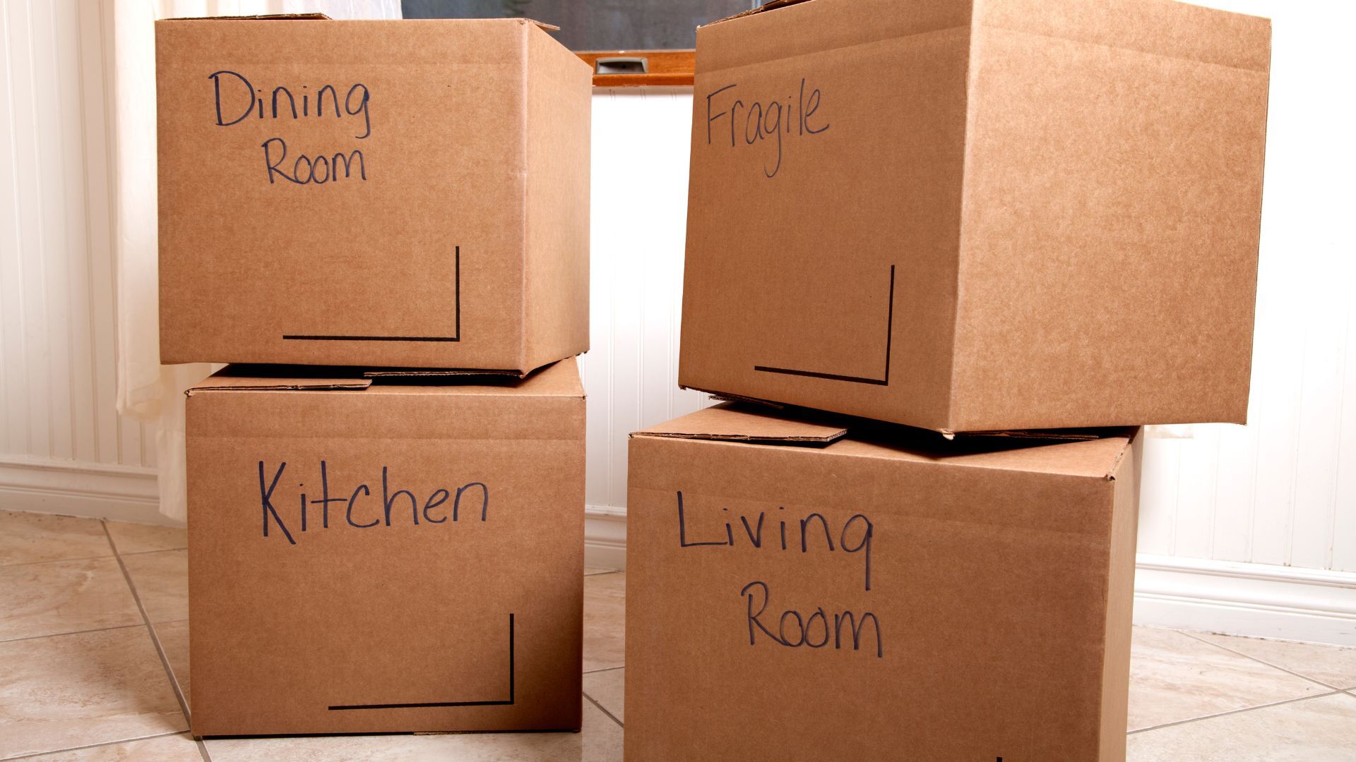 Moving boxes labeled by room and ready to load