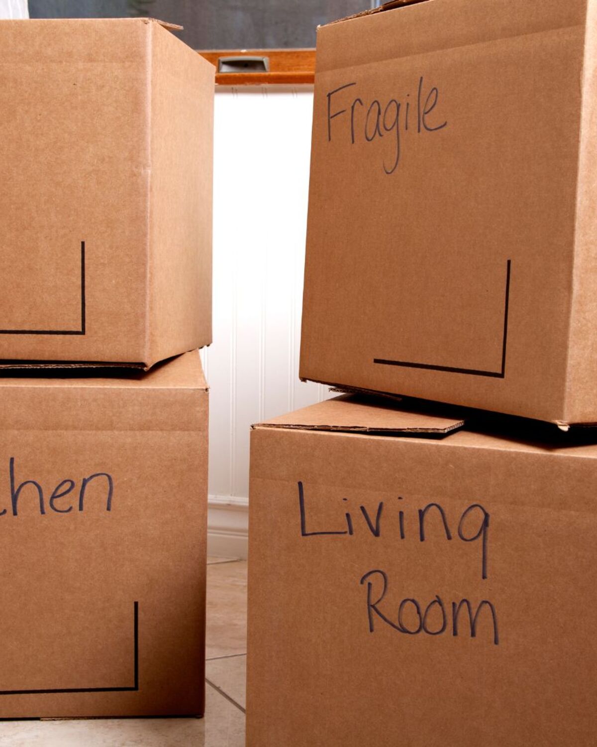 Moving boxes labeled by room with marker, packed and sealed