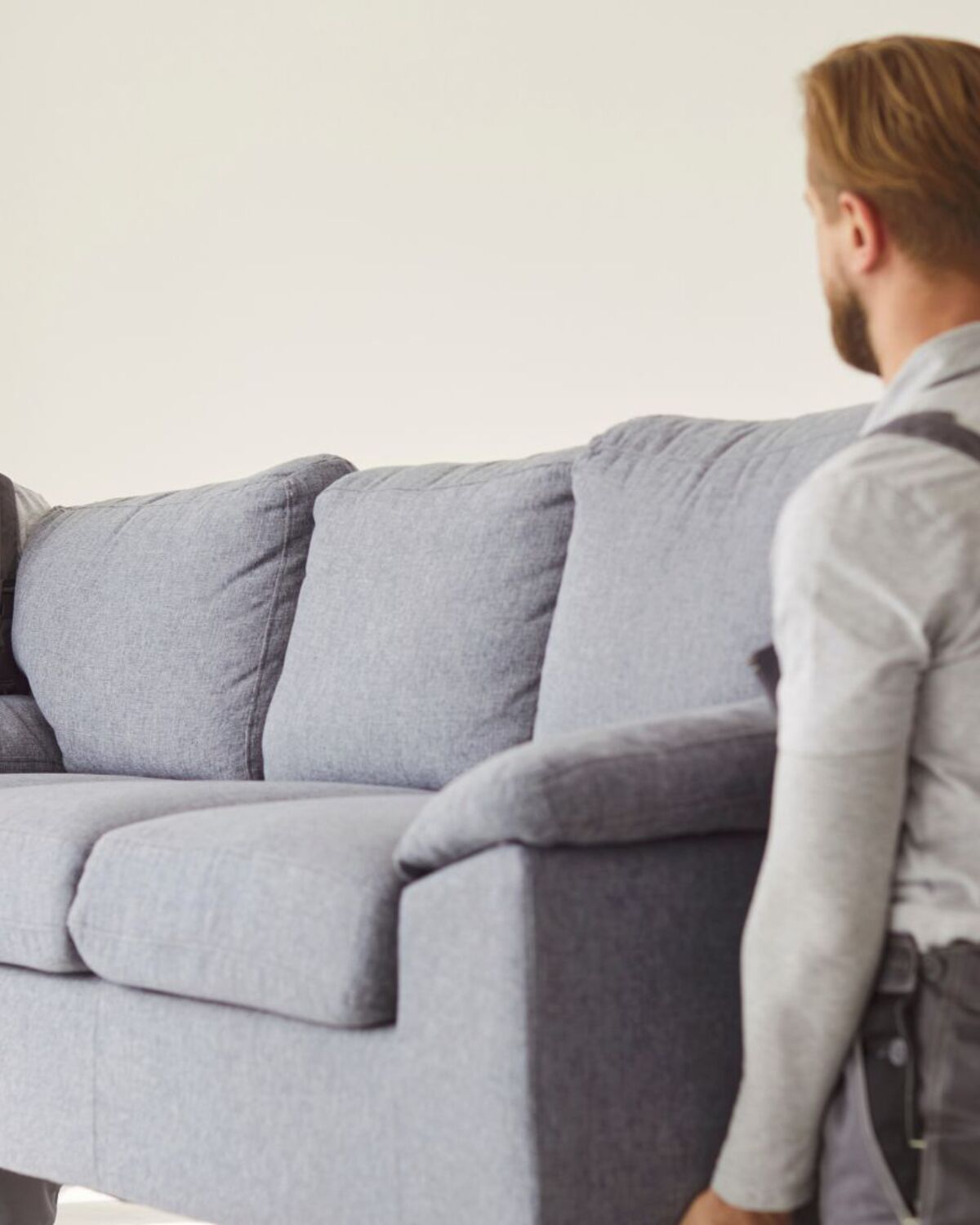 Two movers carrying a sofa through a bright empty room