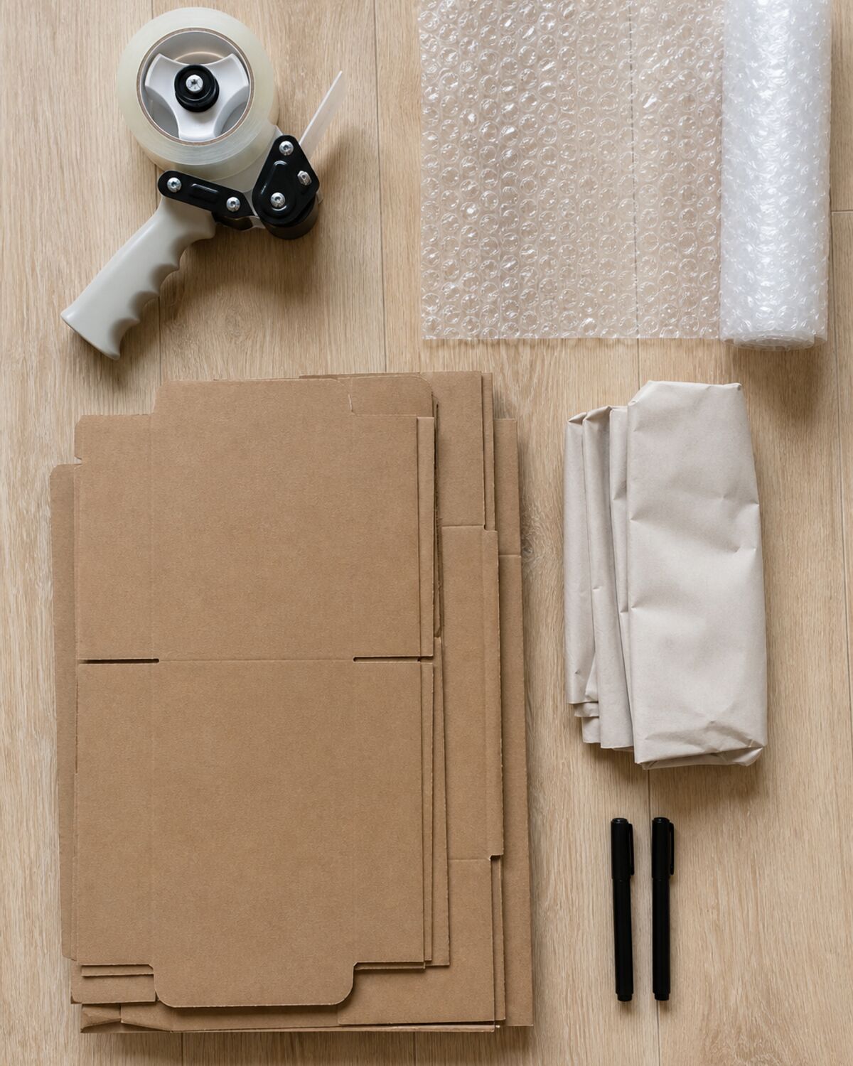 Packing supplies including tape gun, bubble wrap, and flat boxes