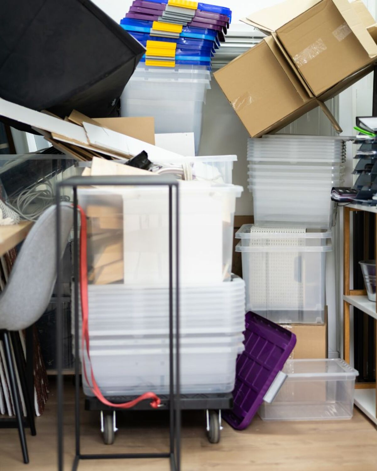 Cluttered storage room with bins, chairs, and boxes awaiting removal